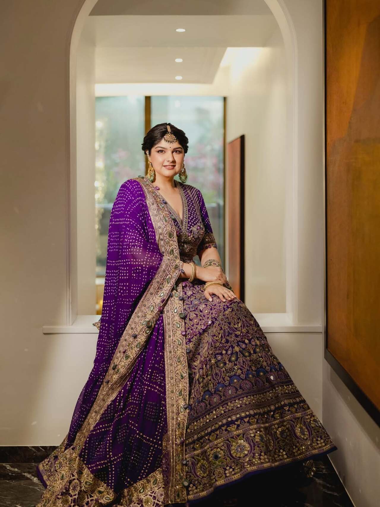 Anshula Kapoor dazzled at the engagement ceremony in a magnificent traditional outfit. She wore a deep purple lehenga choli adorned with intricate gold embroidery and bandhani-style choli. She paired the attire with maang tikka and traditional jhumkas.